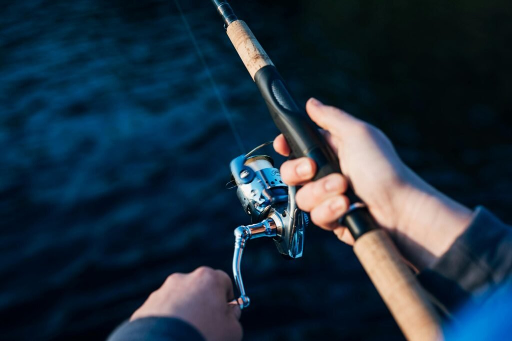 Hands holding a fishing rod over water, perfect for leisure and hobby themes.